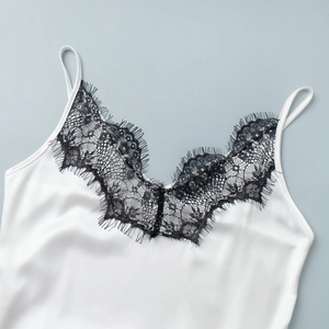 Détail d'un caraco en satin blanc avec bordure en dentelle de cils noire délicate