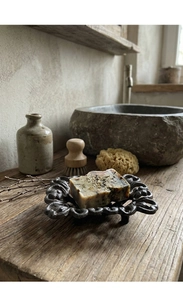 Macro detail of herbal soap with dry petals on a vintage hollowed cast iron soap dish