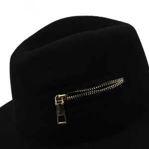 Detail of a black wool fedora featuring a stylish gold metal zipper on the side