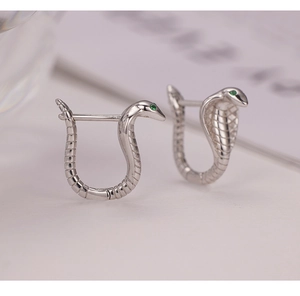 Macro shot of S925 sterling silver cobra earrings with green stone eyes and textured scales