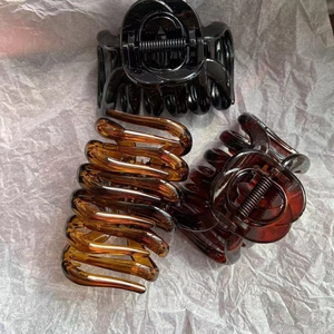 Detailed view of three glossy resin claw clips in black, amber, and dark brown colors
