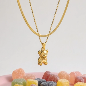 Detailed view of layered gold teddy bear pendant necklace with snake and bead chains