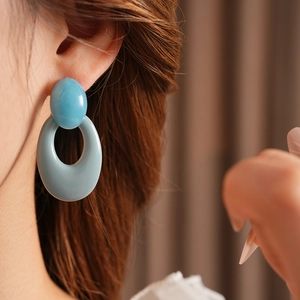 Detail of vintage blue resin oval drop earring worn by model with high gloss finish