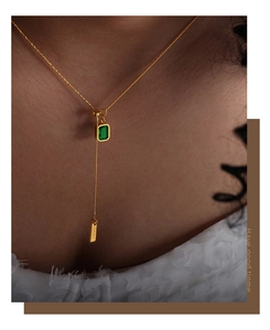 Close-up of gold chain necklace with green emerald-cut zircon and BABY charm