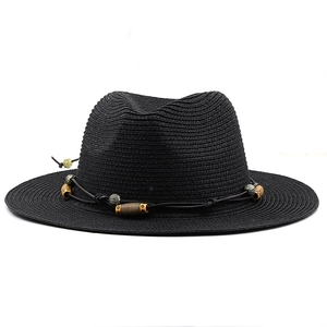 Gros plan d'un chapeau fedora en paille noire avec ruban perlé de style ethnique