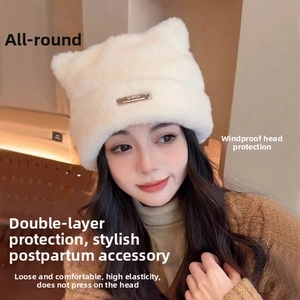 Detail of white faux fur cat ear beanie with soft plush texture and metal brand tag