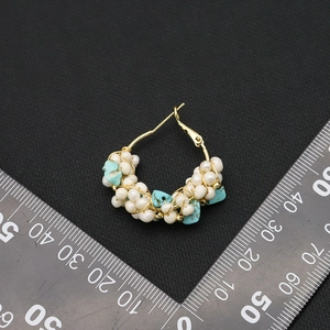 Natural pearl and turquoise beaded gold hoop earrings with retro aesthetic on dark background