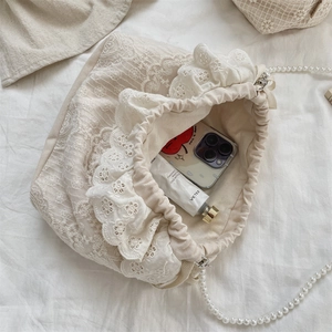 Close-up of lace bucket bag showing interior space for phone and cream with pearl strap