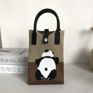 Detail of knitted panda tote bag showing magnetic snap closure and woven texture