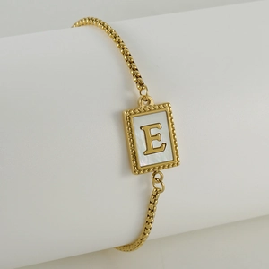 Close-up of gold box chain bracelet with mother of pearl shell initial E square charm