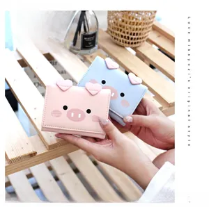 Close-up of cute cartoon pig tri-fold wallets in pink and blue with heart 3D details