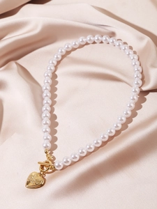 Detailed close-up of a vintage baroque pearl necklace with a gold heart Love you pendant