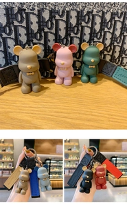 Close-up of bear keychain with colorful soft rubber body and embossed leather wrist strap
