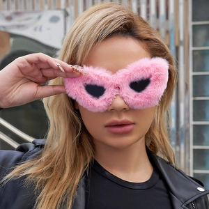 Close-up of pink fuzzy heart-shaped sunglasses with black lenses worn by a model