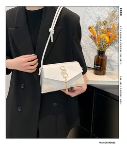 Detail of cream white leather crossbody bag with gold logo fringe and crocodile pattern
