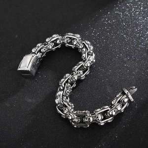 Detailed view of punk style silver stainless steel skull link bracelet on dark background