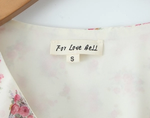 Close-up of V-neck collar label and floral pattern on cream long sleeve dress
