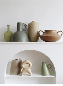 Close-up of matte ceramic art vases in earthy tones inside a white minimalist niche