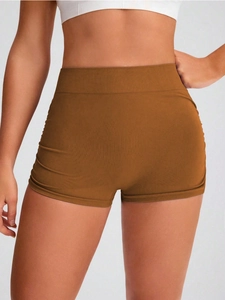 Detail of high-waist seamless knit yoga shorts in caramel brown with peach lift texture