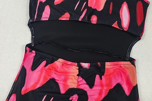 Detail of dress featuring cutout waist, ruched back, and abstract black and pink print