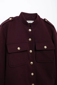 Dettaglio della giacca in lana bordeaux scuro con bottoni metallici dorati e tasche a patta