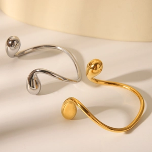 Close-up of gold and silver asymmetrical stainless steel bangles with teardrop ends