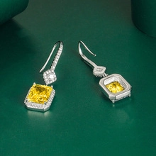 Detail of luxury emerald cut yellow gemstone drop earrings with halo diamond setting