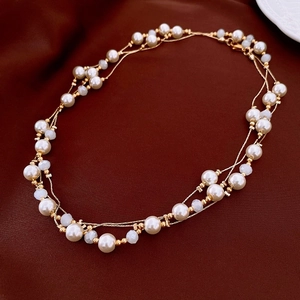 Detail of vintage double-layer necklace with oval pearls and gold chain on satin background