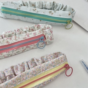 Detail of floral pencil cases with ruffled edges and large ring pull zippers