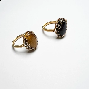 Macro detail of handmade 14K gold wire wrapped rings with tiger eye and blue goldstone