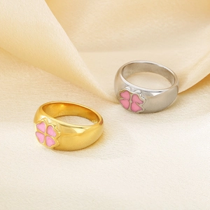 Detailed view of 10mm wide gold and silver heart rings with pink four-leaf clover enamel