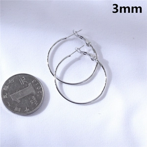 Detail of 3mm thick large silver hoop earrings with a coin for size reference comparison