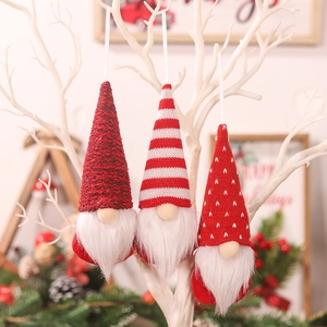 Three-piece set of knitted Christmas Gnomes hanging on a white branch for tree decoration