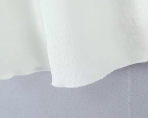 Vue détaillée de la texture du tissu en satin jacquard blanc sur l'ourlet de la jupe
