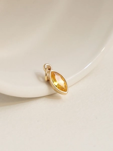 Detail of 18K gold plated marquise-cut yellow zircon pendant on white ceramic plate