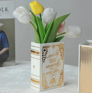 Detail of white ceramic book vase with gold lettering and colorful tulips on top