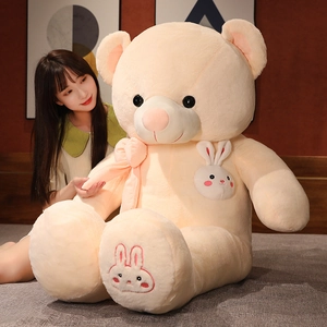 Close-up of a large cream teddy bear plush showing soft fur and pink bow details