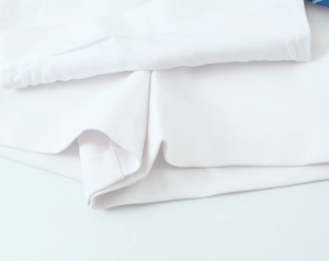 Detailed macro view of white floral print top fabric texture and waist stitching