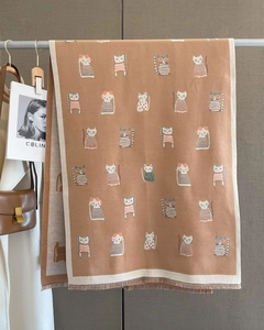 Detail of soft brown knit scarf featuring cartoon cat patterns and delicate fringe edges