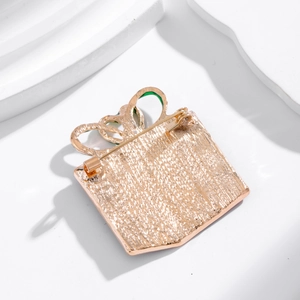 Golden Christmas gift box brooch with enamel bow tie design from a back-side perspective