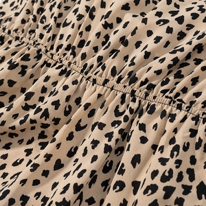 Detail of leopard print satin dress featuring elastic smocked texture and fabric finish