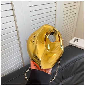Detailed view of a gold metallic sculpted clutch bag with organic shape and chain strap