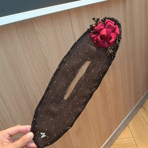 Detail of red satin flower bun maker with black mesh and delicate white polka dots