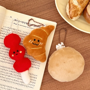 Close-up of cute cartoon food plush pendants with metal chains on a book
