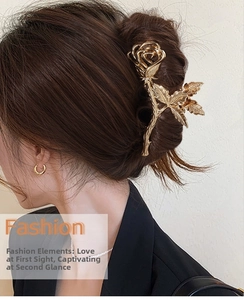 Détail d'une pince à cheveux en métal doré avec rose évidée sur une coiffure arrière