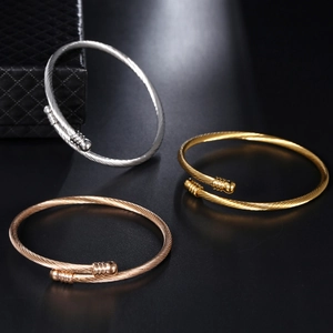 Detailed macro view of silver, gold, and rose gold twisted cable open cuff bracelets