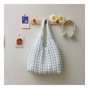 Detail of light blue pleated cloud tote bag with puffy floral texture on a wooden hanger