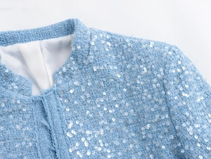 Detail of light blue tweed jacket showing intricate weave and white sequin embellishments