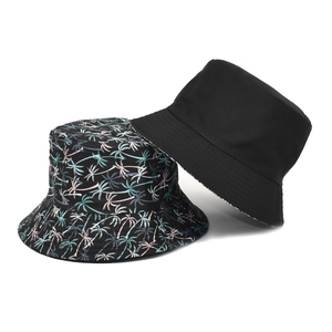 Double-sided reversible bucket hat featuring tropical palm print and solid black cotton canvas