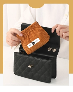 Close-up of orange corduroy pouch being placed into a black quilted handbag bag